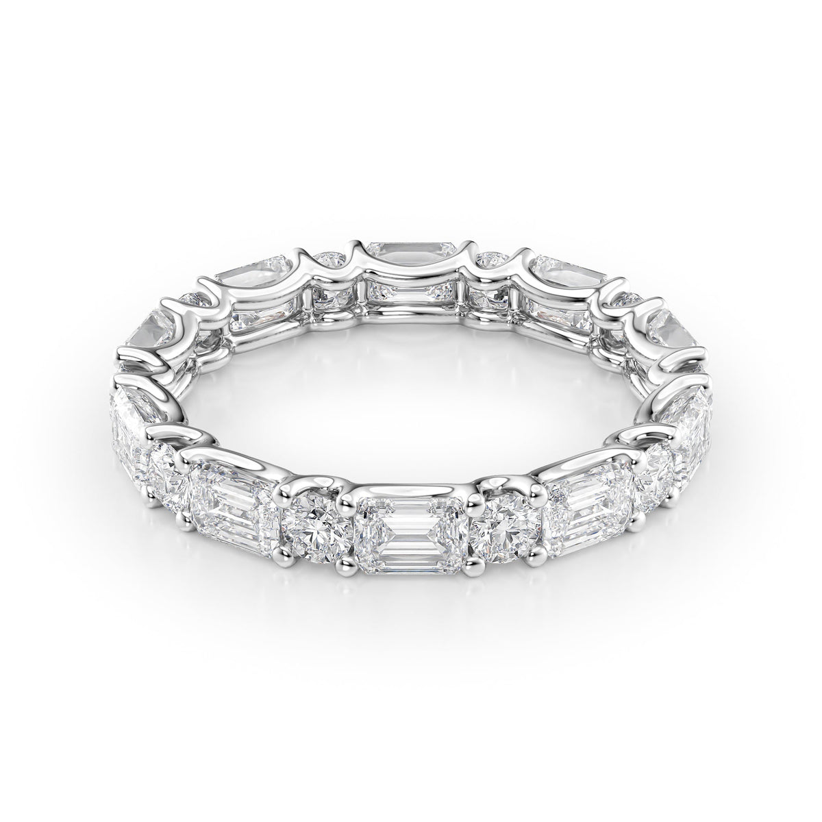 3.2ct Alternating Emerald And Round U Prong Eternity. A White Gold Eternity Ring Set With 2.5tcw Emerald Lab Grown Diamonds. White Background.