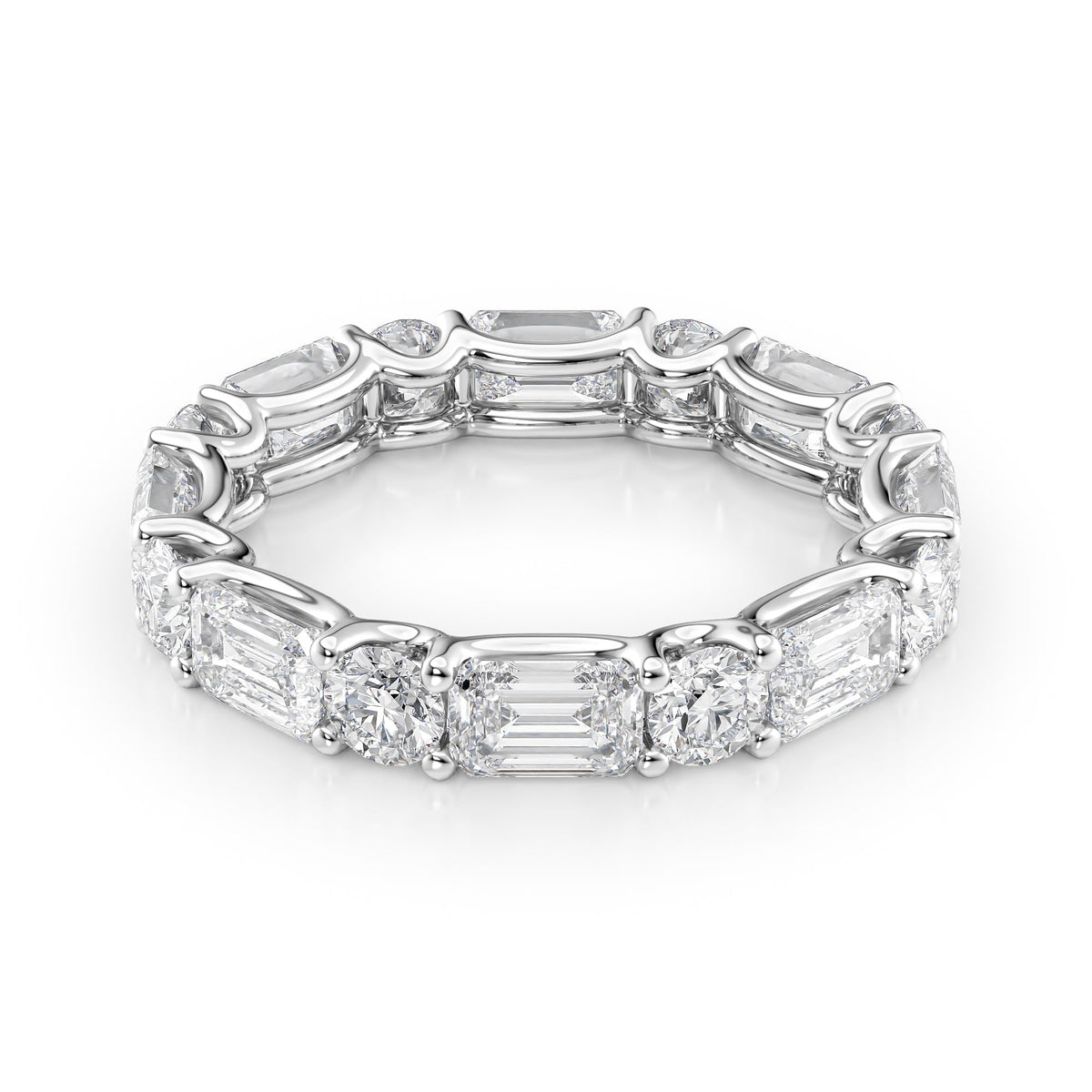 4.2ct Alternating Emerald And Round U Prong Eternity. A White Gold Eternity Ring Set With 3.2tcw Emerald Lab Grown Diamonds. White Background.