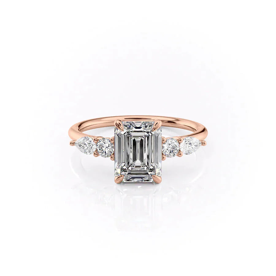 The Abigail. A Rose Gold Three Stone, Side Stones Engagement Ring Set With A 2ct Emerald Lab Grown Diamond. White Background.