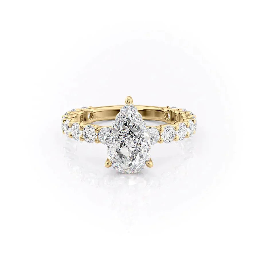 The Adelle. A Yellow Gold Side Stones, Hidden Halo Engagement Ring Set With A 2ct Pear Lab Grown Diamond. White Background.