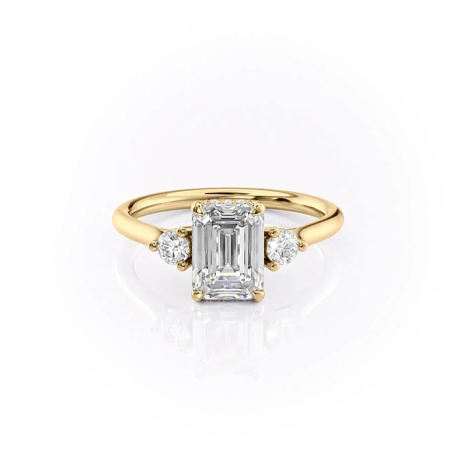 The Lia. A Yellow Gold Three Stone Engagement Ring Set With A 2ct Emerald Lab Grown Diamond. White Background.