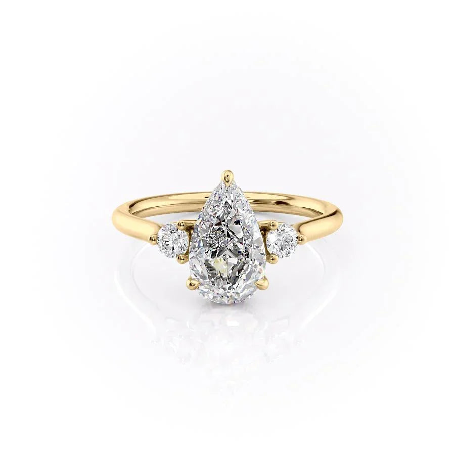 The Lia. A Yellow Gold Three Stone Engagement Ring Set With A 2ct Pear Lab Grown Diamond. White Background.