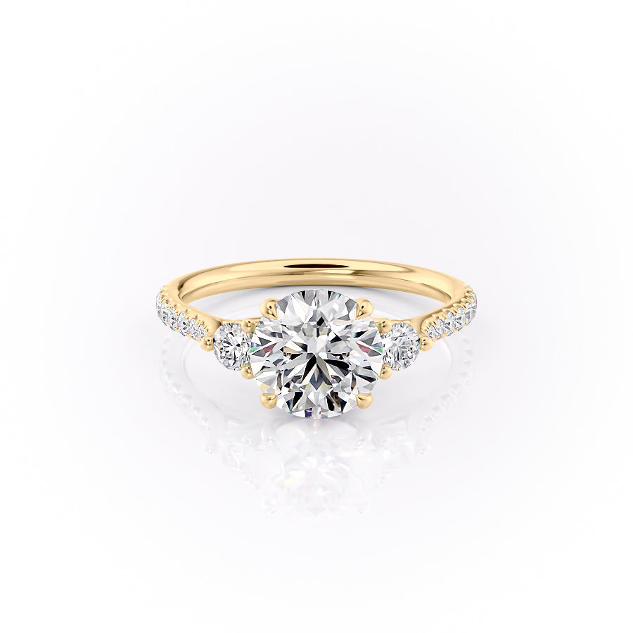 The Pave Lia. A Yellow Gold Three Stone Engagement Ring Set With A 2ct Round Lab Grown Diamond. White Background.