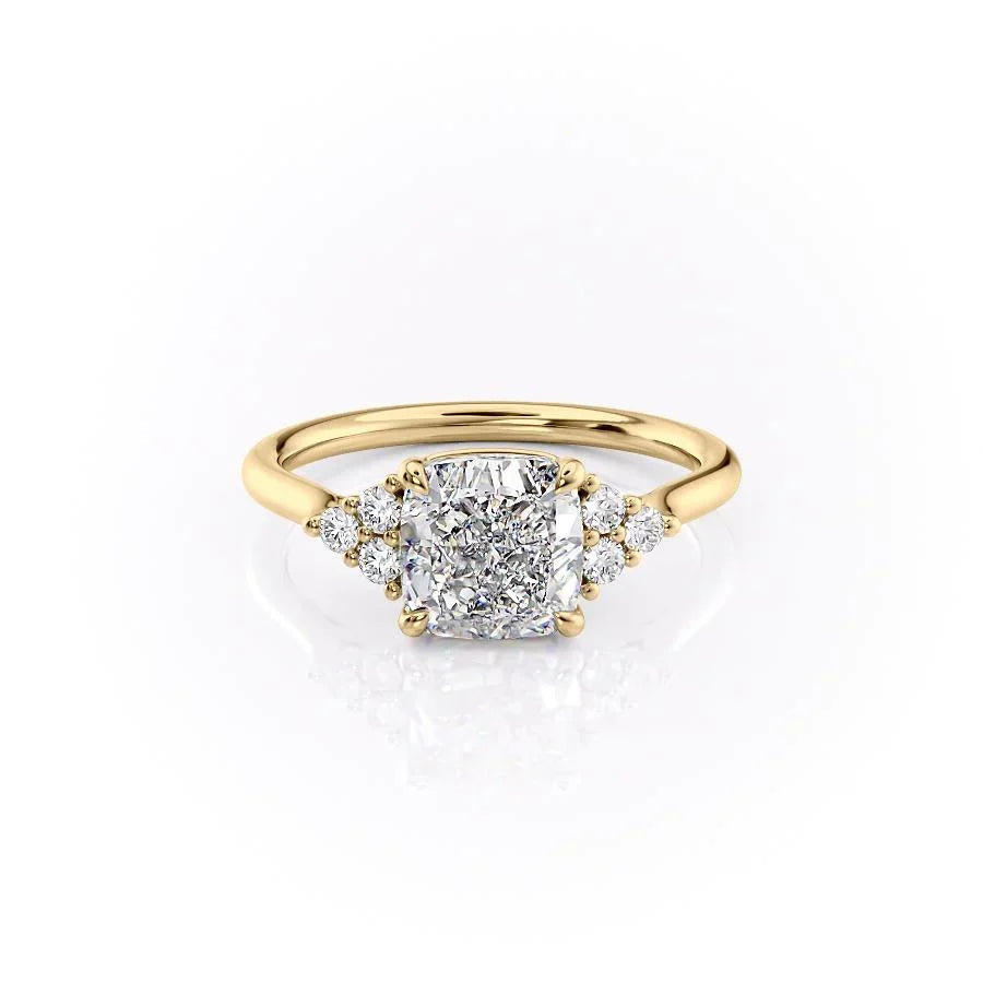 The Scarlett. A Yellow Gold Side Stones, Three Stone Engagement Ring Set With A 2ct Cushion Lab Grown Diamond. White Background.