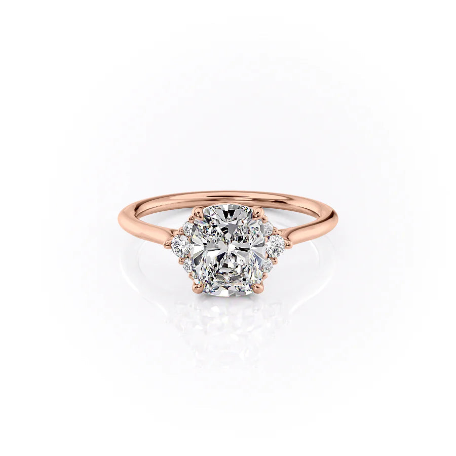 The Victoria. A Rose Gold Three Stone, Side Stones Engagement Ring Set With A 2ct Elongated Cushion Lab Grown Diamond. White Background.