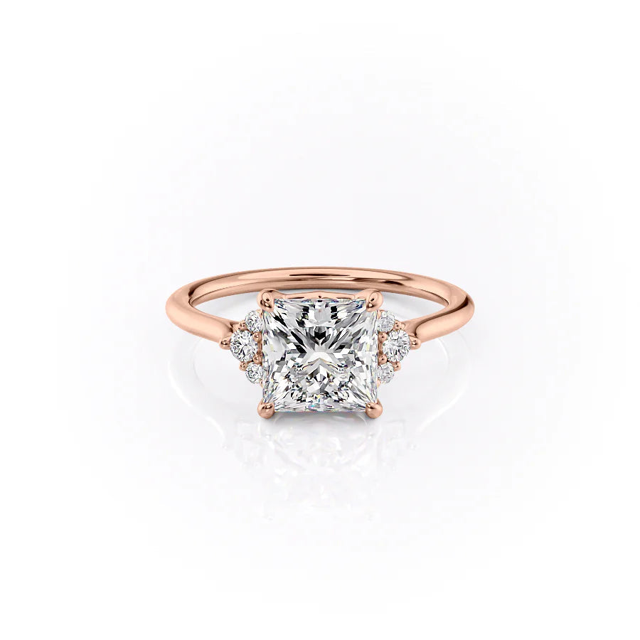 The Victoria. A Rose Gold Three Stone, Side Stones Engagement Ring Set With A 2ct Princess Lab Grown Diamond. White Background.