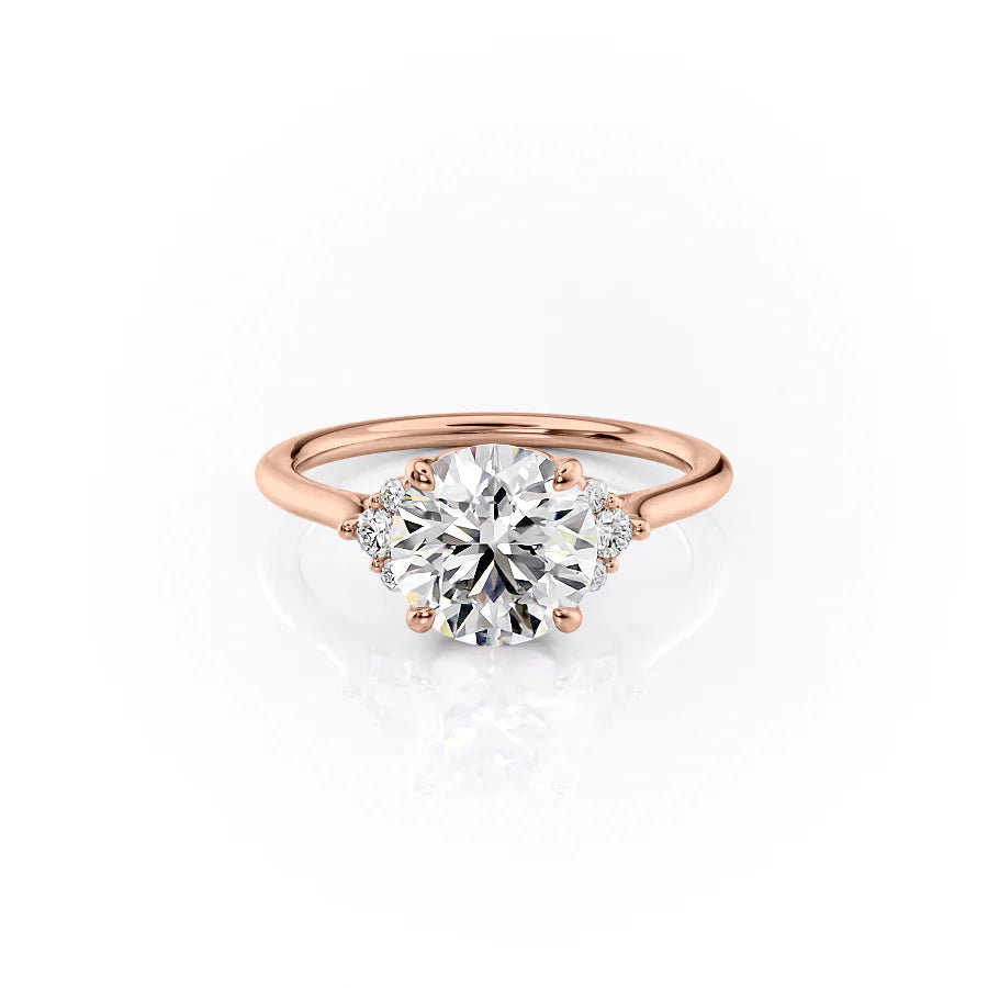 The Victoria. A Rose Gold Three Stone, Side Stones Engagement Ring Set With A 2ct Round Lab Grown Diamond. White Background.