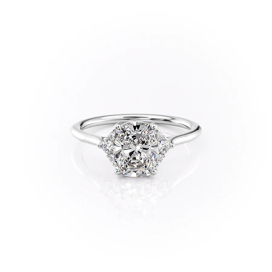The Victoria. A White Gold Three Stone, Side Stones Engagement Ring Set With A 2ct Elongated Cushion Lab Grown Diamond. White Background.