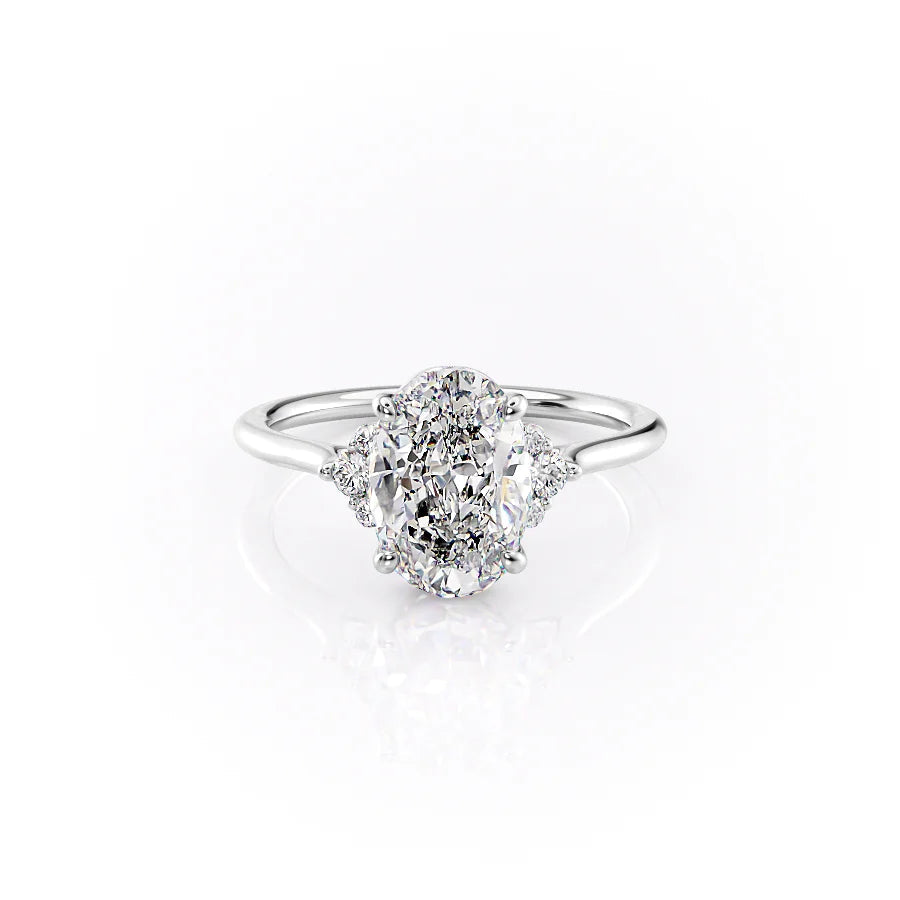 The Victoria. A White Gold Three Stone, Side Stones Engagement Ring Set With A 2ct Oval Lab Grown Diamond. White Background.
