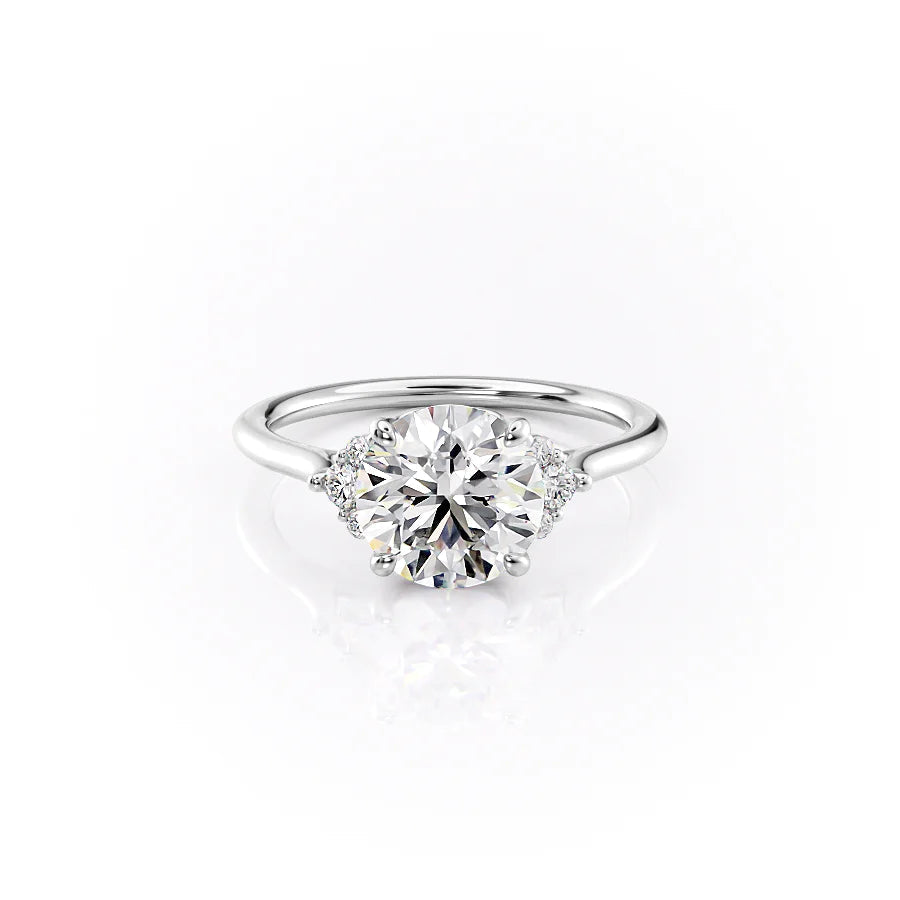 The Victoria. A White Gold Three Stone, Side Stones Engagement Ring Set With A 2ct Round Lab Grown Diamond. White Background.