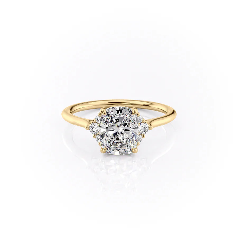 The Victoria. A Yellow Gold Three Stone, Side Stones Engagement Ring Set With A 2ct Elongated Cushion Lab Grown Diamond. White Background.