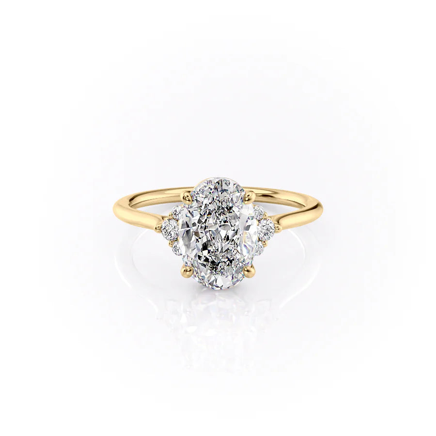 The Victoria. A Yellow Gold Three Stone, Side Stones Engagement Ring Set With A 2ct Oval Lab Grown Diamond. White Background.