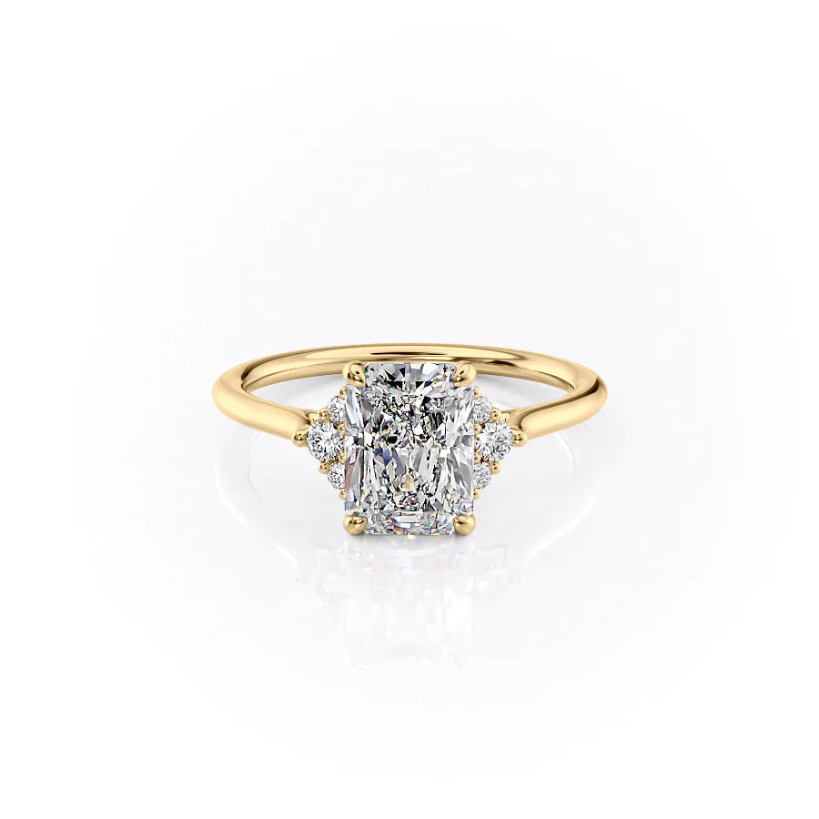 The Victoria. A Yellow Gold Three Stone, Side Stones Engagement Ring Set With A 2ct Radiant Lab Grown Diamond. White Background.